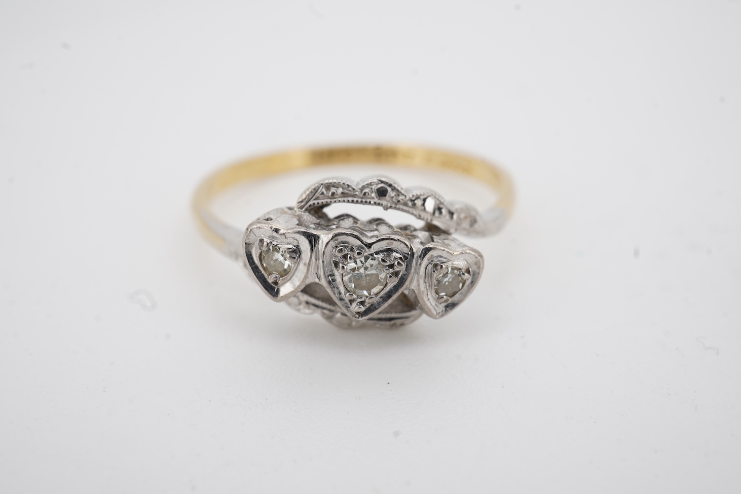 A mid 20th century 18ct, plat. and three stone diamond chip crossover ring, each stone in a heart shaped setting, size Q, together with an 18ct and fourteen stone diamond set two row ring, size P/Q, gross weight 6 grams.